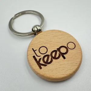 A round wooden keychain with the "tokeepo" logo engraved on its surface, attached to a silver keyring, placed on a white background.