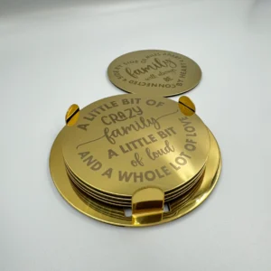 A gold stainless steel coaster set with an engraved family quotes, neatly stacked in a matching holder.