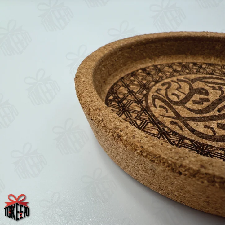 Angled close-up of cork coaster edge showing thickness and laser engraved border and Arabic design.