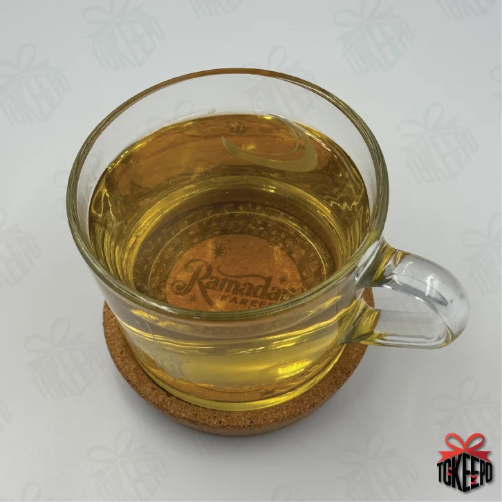 Glass tea cup resting on a Ramadan Kareem laser engraved cork coaster.