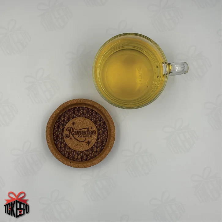 Top view of glass tea mug and Ramadan Kareem cork coaster on a white background.