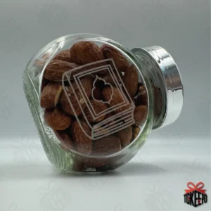 Engraved glass reward jar labeled for Quran, filled with almonds and shown on its side with a silver lid.