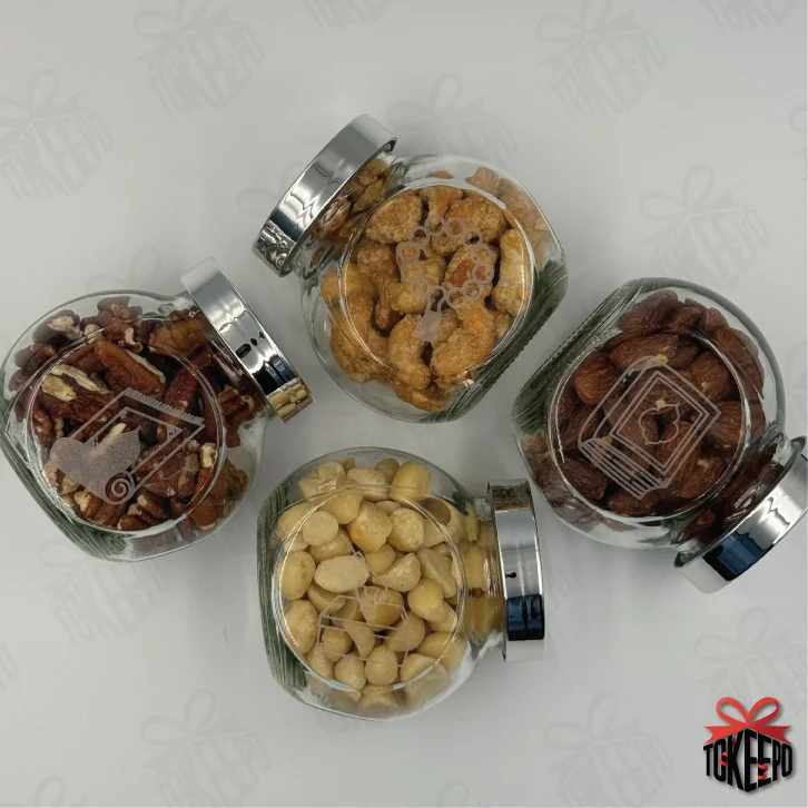 Set of four engraved glass reward jars with silver lids, filled with snacks and arranged in a flat lay.